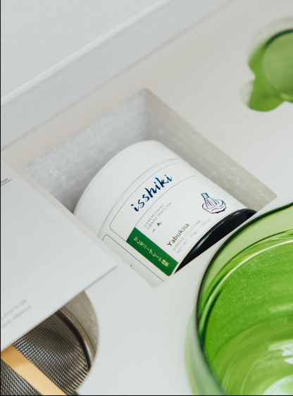 Isshiki Yabukita matcha tin tucked into the gift box beside the green Hario glass bowl