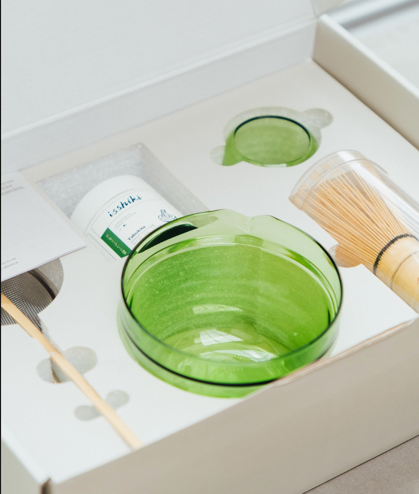 Green Hario glass bowl, isshiki matcha tin, and bamboo whisk nestled in the set's white gift box