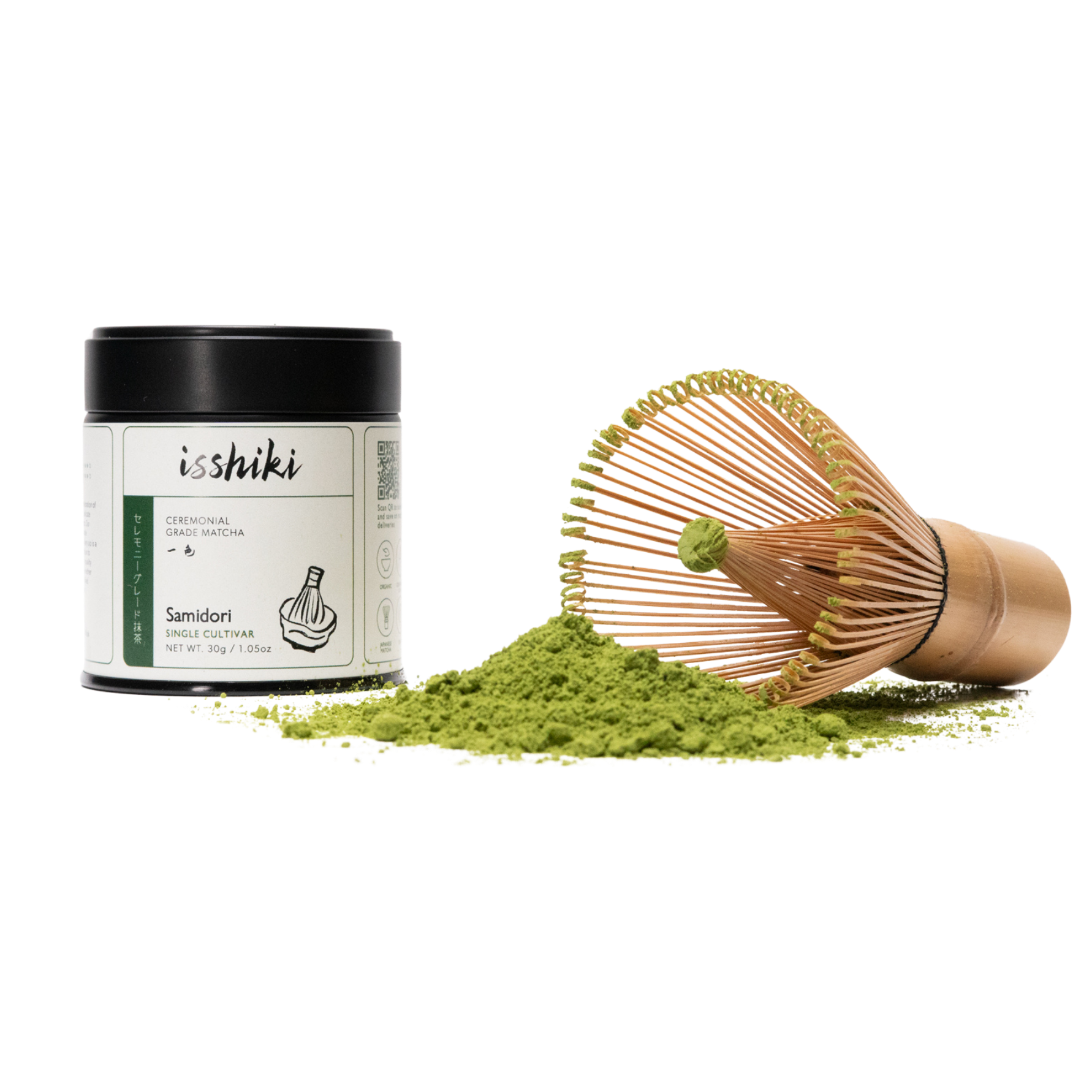 Isshiki Samidori ceremonial matcha tin beside a bamboo whisk resting on a mound of green matcha powder