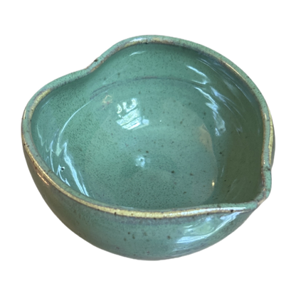 Glossy green heart-shaped matcha bowl with speckled glaze and pouring spout, seen from above