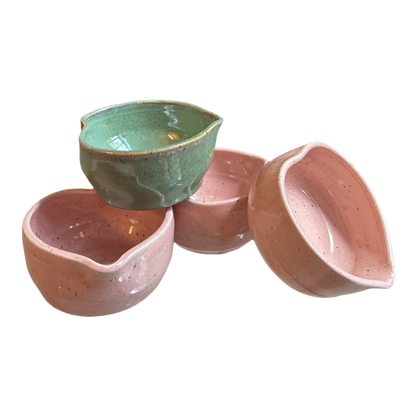 Four handcrafted heart-shaped matcha bowls, one speckled green and three pink, clustered together