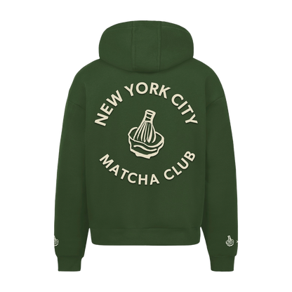 Back of the green hoodie with New York City Matcha Club lettering around a bamboo whisk and bowl graphic