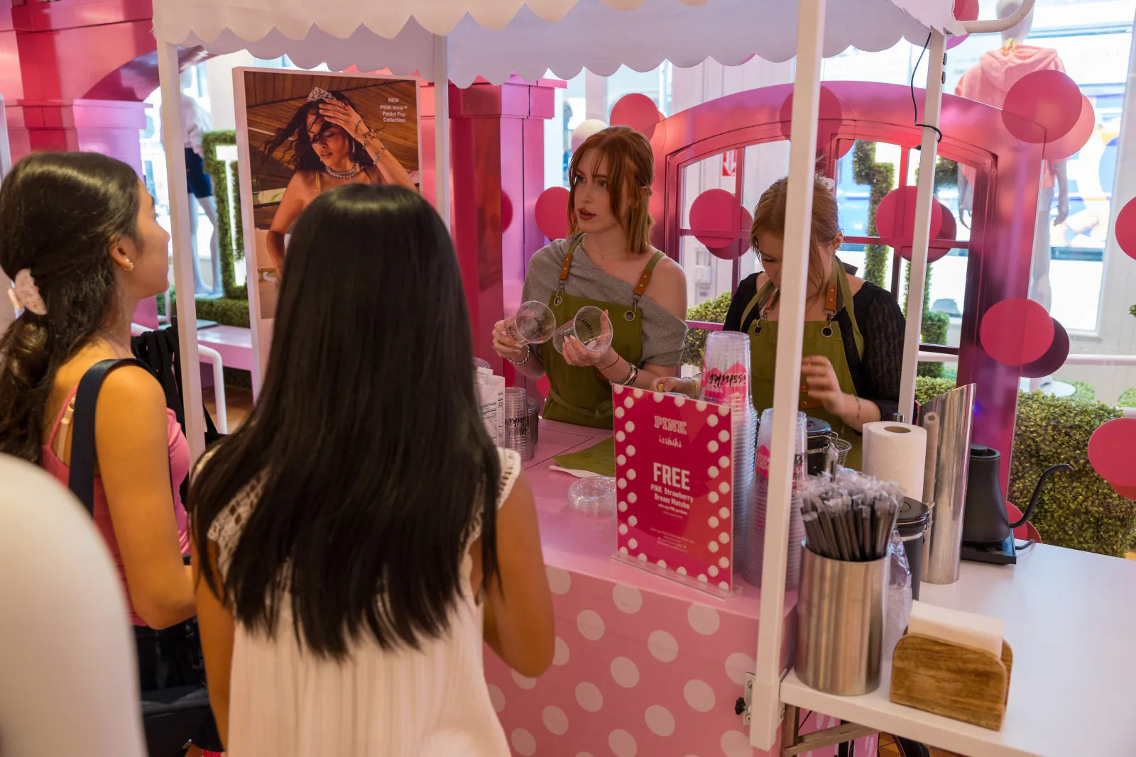 Two Isshiki baristas serving guests from a pink matcha bar at an event