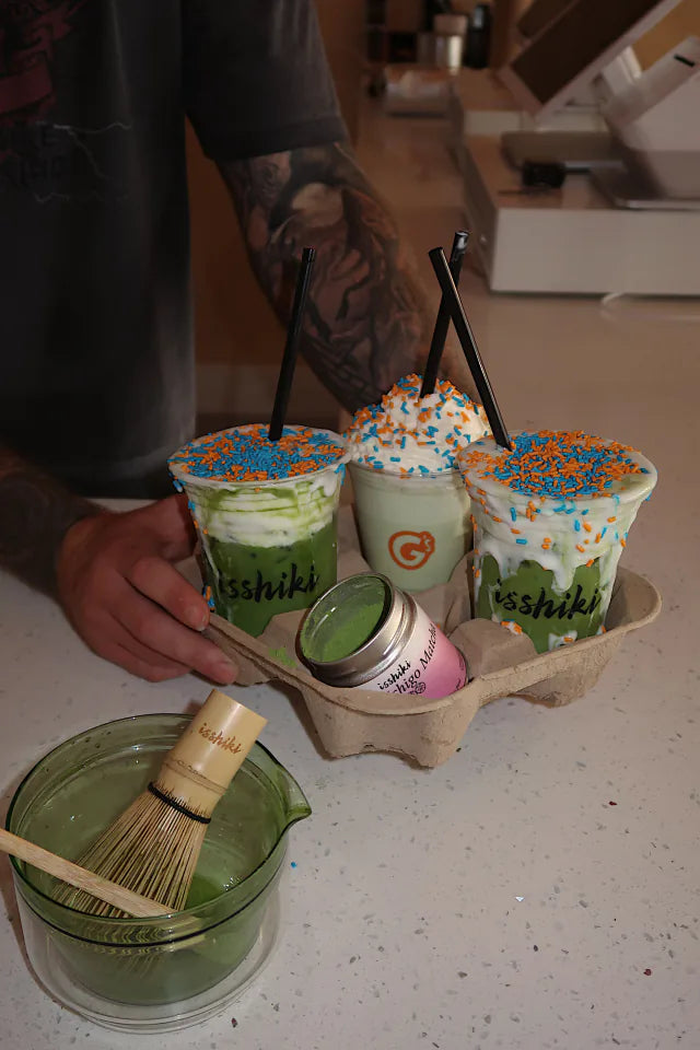 Branded matcha drinks and a bamboo whisk at an event